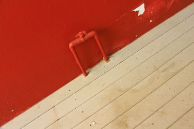 High angle view of wooden floor against red wall