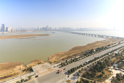 High angle view of road in city by river against sky