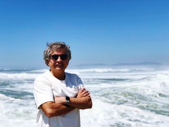 Man wearing sunglasses while standing at beach against sky