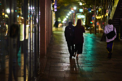 Rear view of women walking on street at night