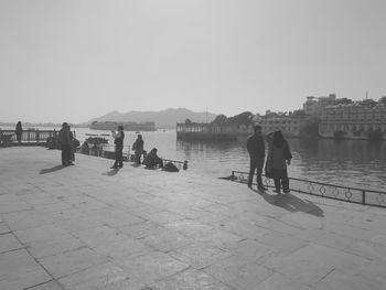 People standing on shore against clear sky