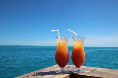 Drinks on wooden railing by sea