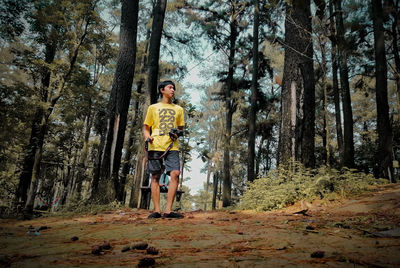 Portrait of man standing by trees in forest