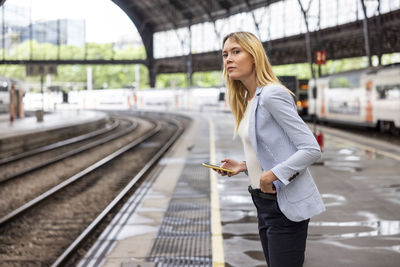 Commuter with smart phone waiting for train at station