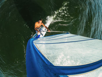 Wide-angle shot of adult man windsurfing on lake wallersee, austria
