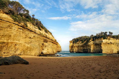 Rock formations on beach against sky