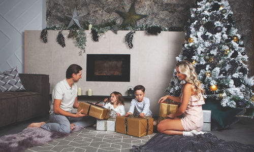 Christmas mood. family open gifts. decorated christmas tree and fireplace on background