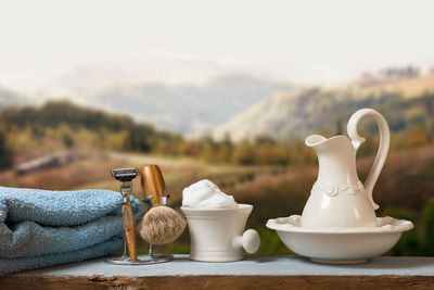 Close-up of shaving equipment and towel on table against field