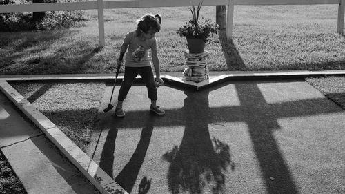 Full length of girl playing miniature golf at lawn