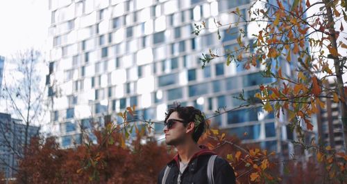 Low angle view of man standing against building during autumn