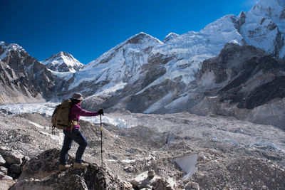 Hiker standing on rock against mountain range 