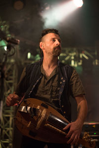 Midsection of man holding illuminated lighting equipment at night