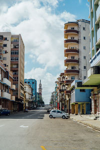 Cars on street in city against sky