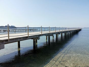 Bridge over calm sea against clear sky