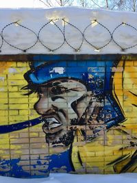 Graffiti on metal fence against blue sky