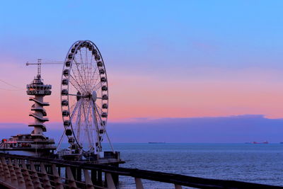 Ferris wheel at sea against sky