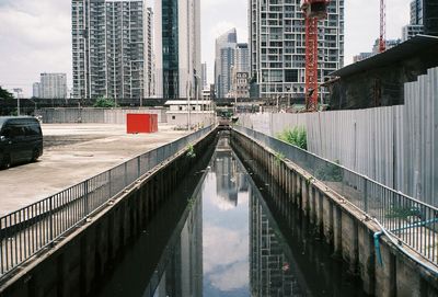 Canal amidst buildings in city against sky