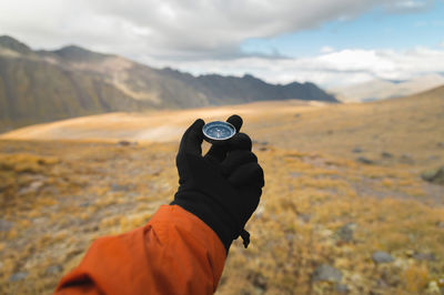 First-person view of a male traveler's hand holding a magnetic compass against the backdrop 