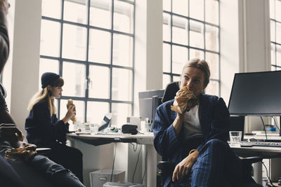 Female entrepreneur eating food while working in office