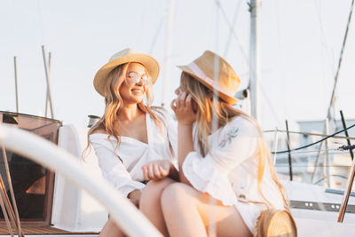 Smiling young woman sitting against boat