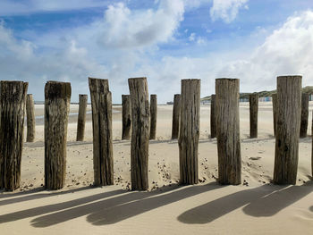 Panoramic view of wooden breakwater posts on beach against sky