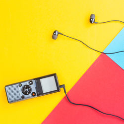 High angle view of recorder with headphones on colored background