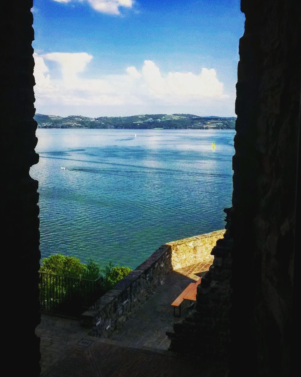 water, sky, sea, built structure, architecture, building exterior, tranquility, tranquil scene, cloud - sky, blue, scenics, cloud, beauty in nature, nature, mountain, day, lake, no people, rock - object, sunlight