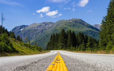 Empty road by mountains against sky