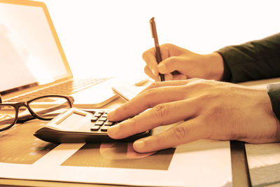 Midsection of person using mobile phone on table