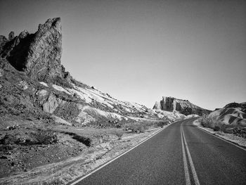 Road by mountain in desert against clear sky