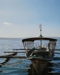 Fishing boat moored on sea against sky