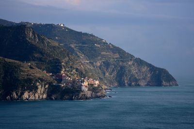 Scenic view of sea by mountains against sky