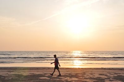 Man on beach against sky during sunset