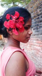 Close-up of woman with pink flower against wall