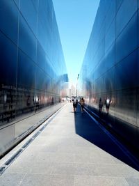 People walking in alley against blue sky