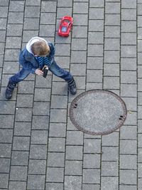 High angle view of boy playing with remote control car on footpath