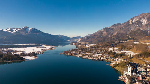 Lake by mountains against clear blue sky