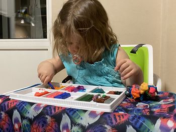 Girl playing with clay on table at home