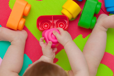 Low section of baby girl playing with toys at home