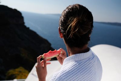 Close-up of woman having watermelon while looking at sea