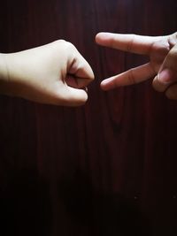 Cropped hands of people gesturing against wooden wall