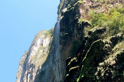 Low angle view of rock formation in sea against clear sky