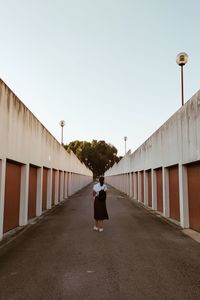 Rear view of woman walking on street against sky