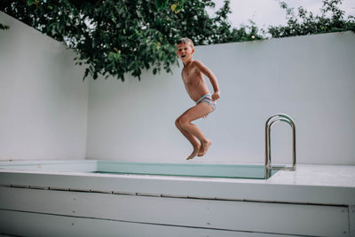 Full length of shirtless man jumping in swimming pool