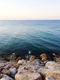 Scenic view of rocks in sea against clear sky