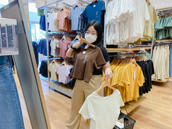 Young woman wear mask is shopping for clothes in shopping center. new normal concept