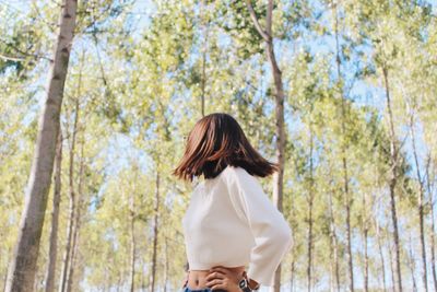 Woman looking at trees while standing in forest