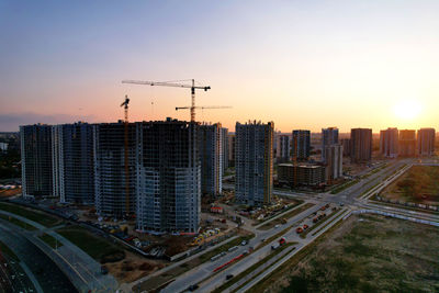 Modern buildings in city against sky during sunset