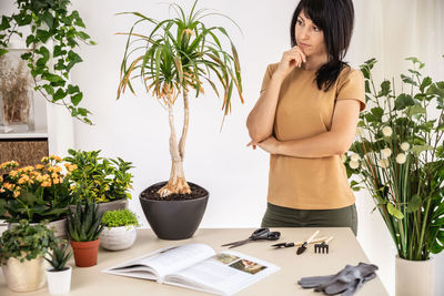 Side view of young woman standing against wall