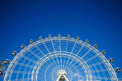 Low angle view of ferris wheel against blue sky